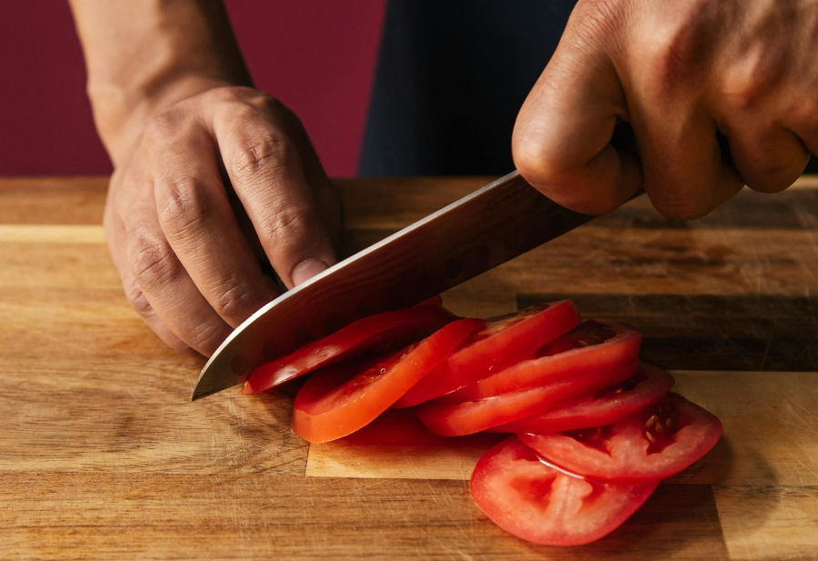 Cuchillo japonés cortando un tomate con precisión